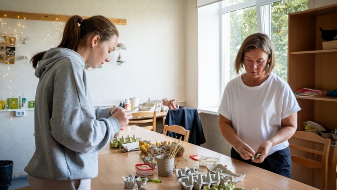 pasniedzēja un jauniete kopā darbojās ar papīru