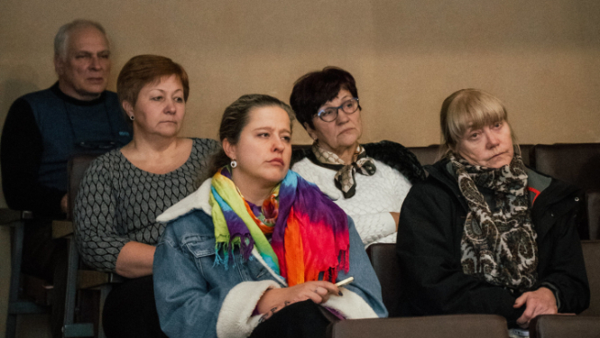 cilvēki sēž un skatās nopietni