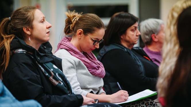 Auditorija klausās, sieviete pieraksta uz lapas