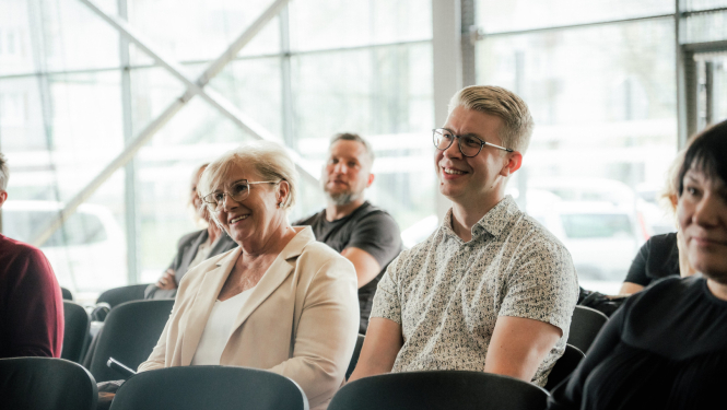 cilvēki sēž un klausās 