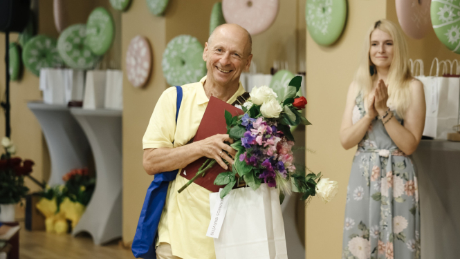 vīrietis ar ziediem rokās smaida