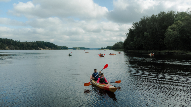 cilvēki laivo pa upi