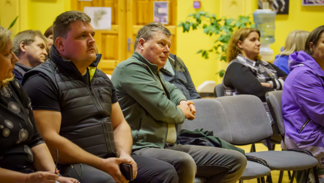 cilvēki sēž un klausās 