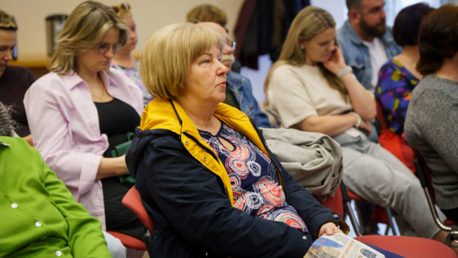 iedzīvotāji sēž un klausās vadībā