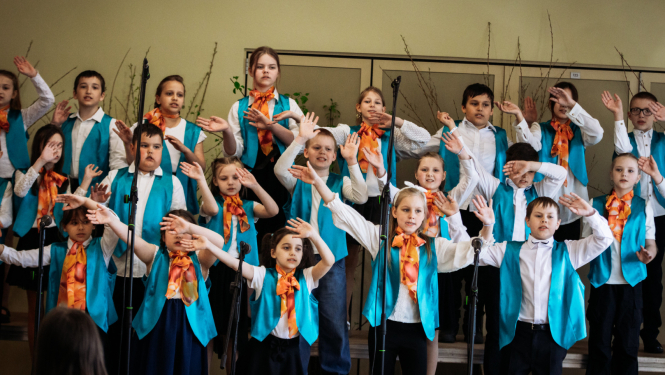 skolas koris dzied un tur rokas gaisā