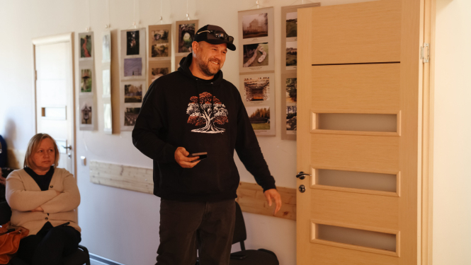 vīrietis piecēlies kājās tur rokās telefonu