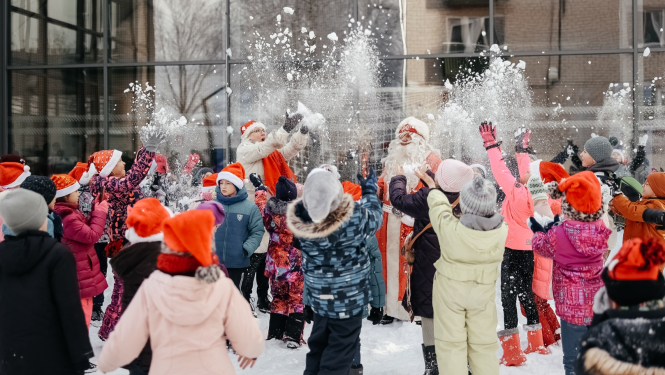bērni kopā ar Ziemassvētku vecīti met gaisā sniegu