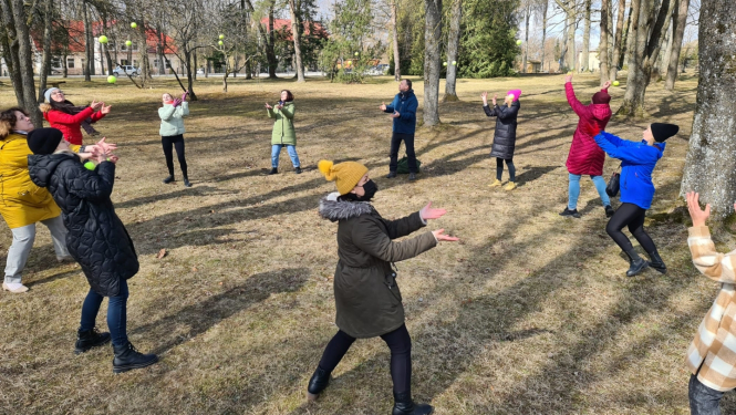 dalībnieki mētā tenisa bumbiņas, stāvot aplī