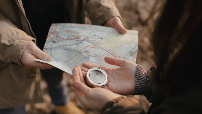 cilvēki tur rokās karti un kompasu