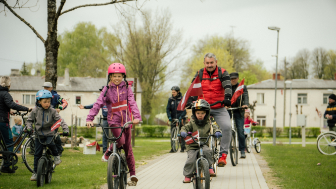 Neretas apvienības pārades vaītājs un bērni 4. maija velo braucienā ar Latvijas karogiem