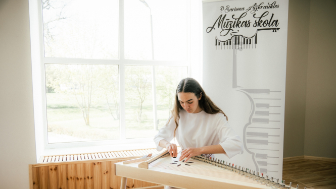 meitene baltā tērpā spēle kokli Aizkraukles mūzikas skolā