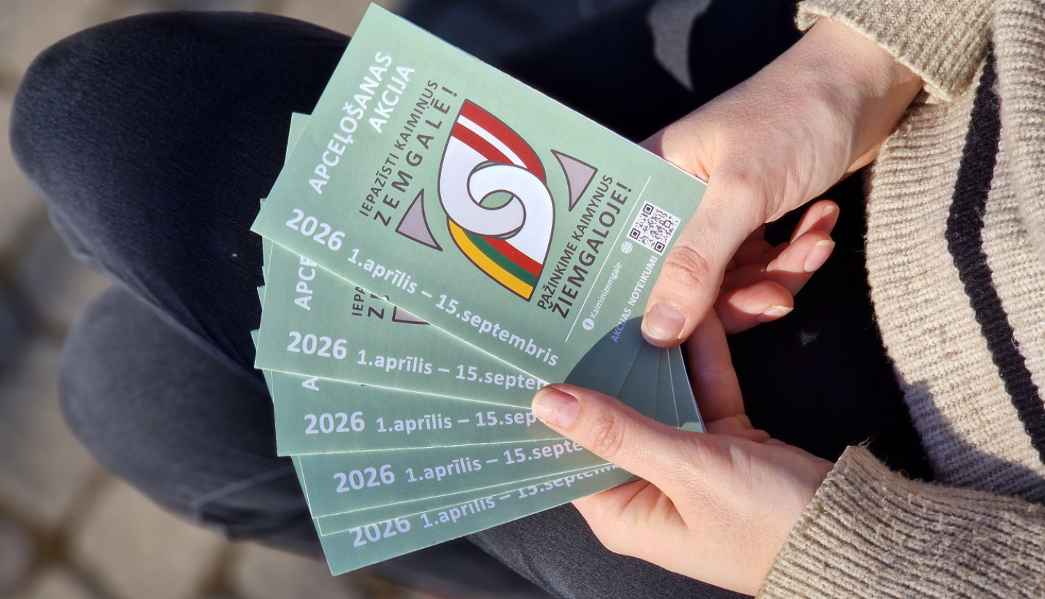 cilvēks tur rokās tūrisma bukletiņus