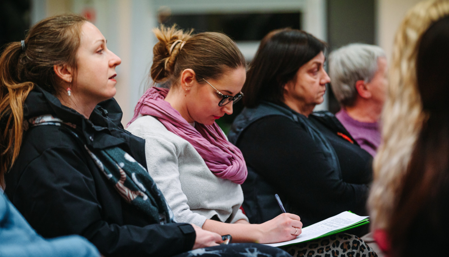 Auditorija klausās, sieviete pieraksta uz lapas