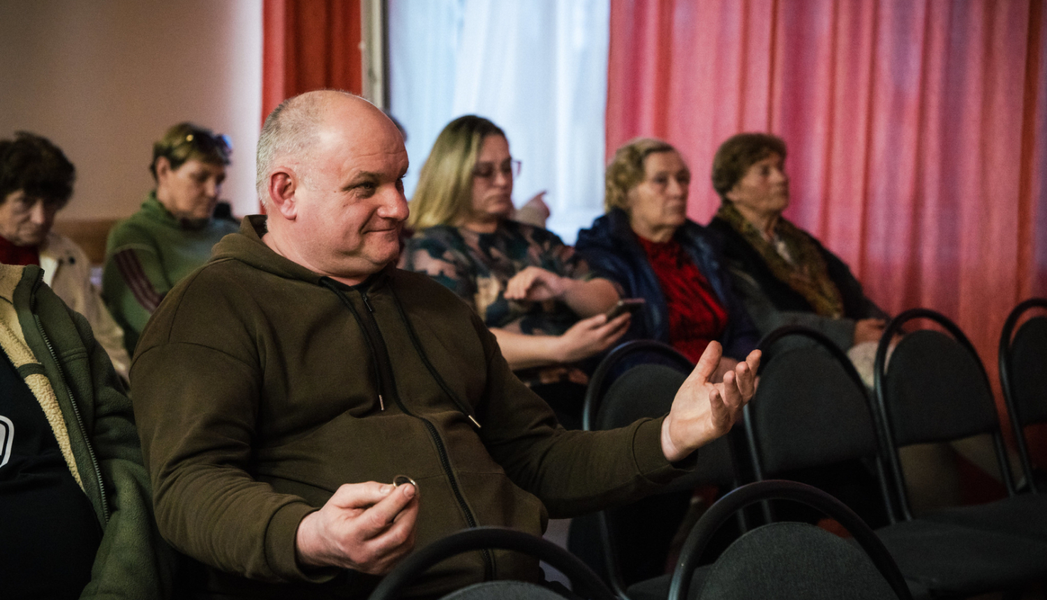 vīrietis rāda ar rokām