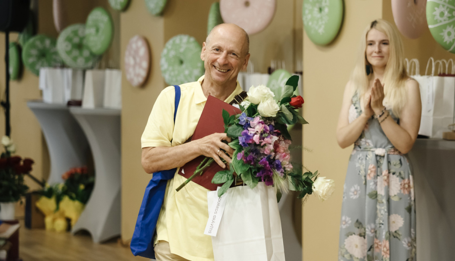 vīrietis ar ziediem rokās smaida