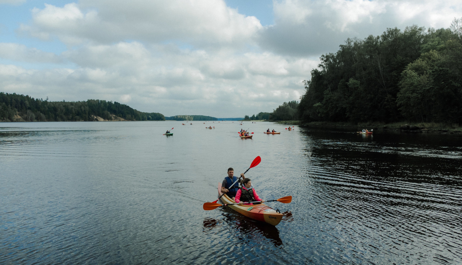 cilvēki laivo pa upi