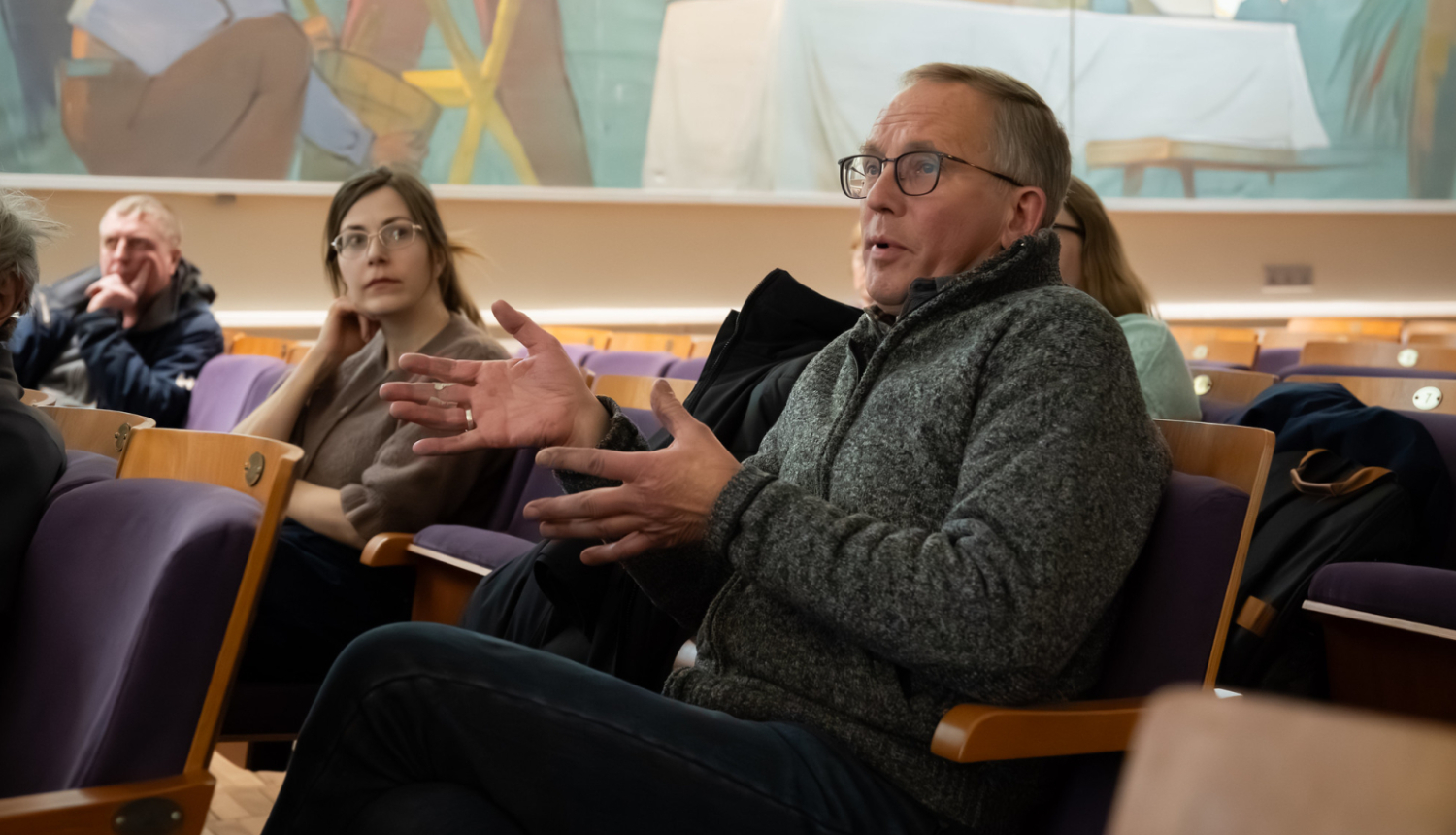 vīrietis sēž uz krēsla un diskutē