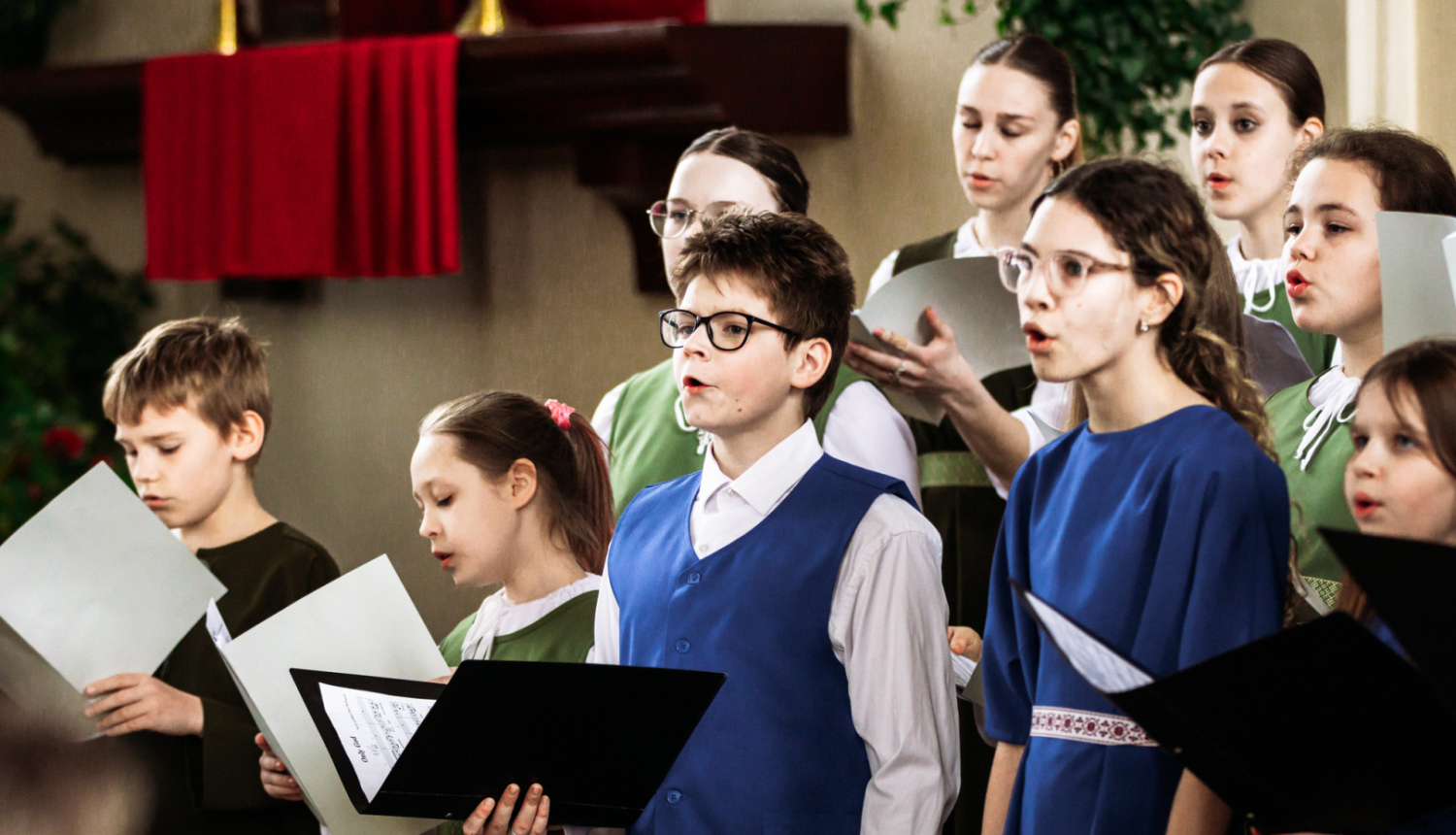 vairāki jaunieši tur rokās mapes un dzied