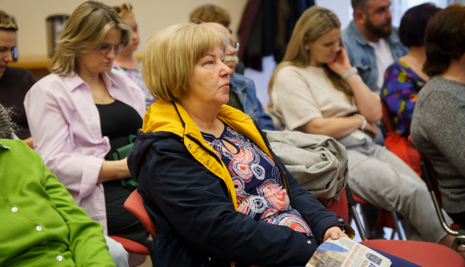 iedzīvotāji sēž un klausās vadībā