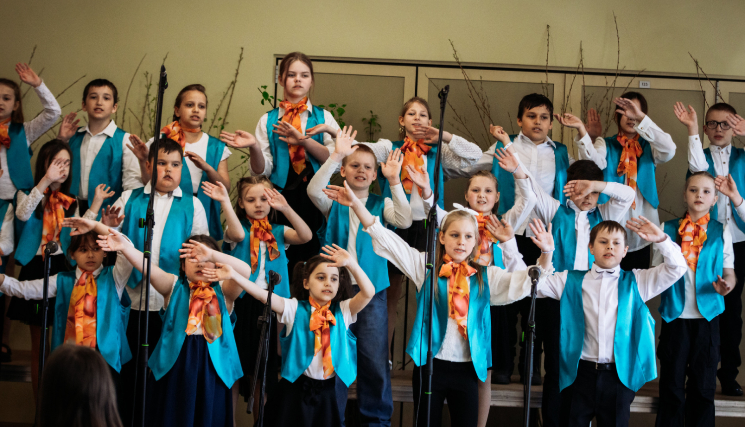 skolas koris dzied un tur rokas gaisā