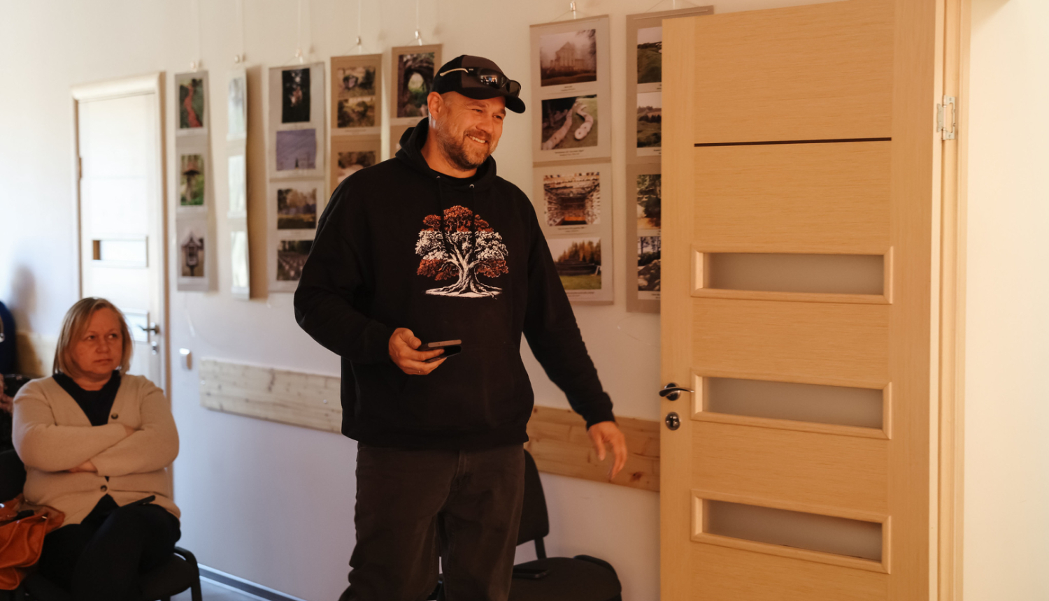 vīrietis piecēlies kājās tur rokās telefonu