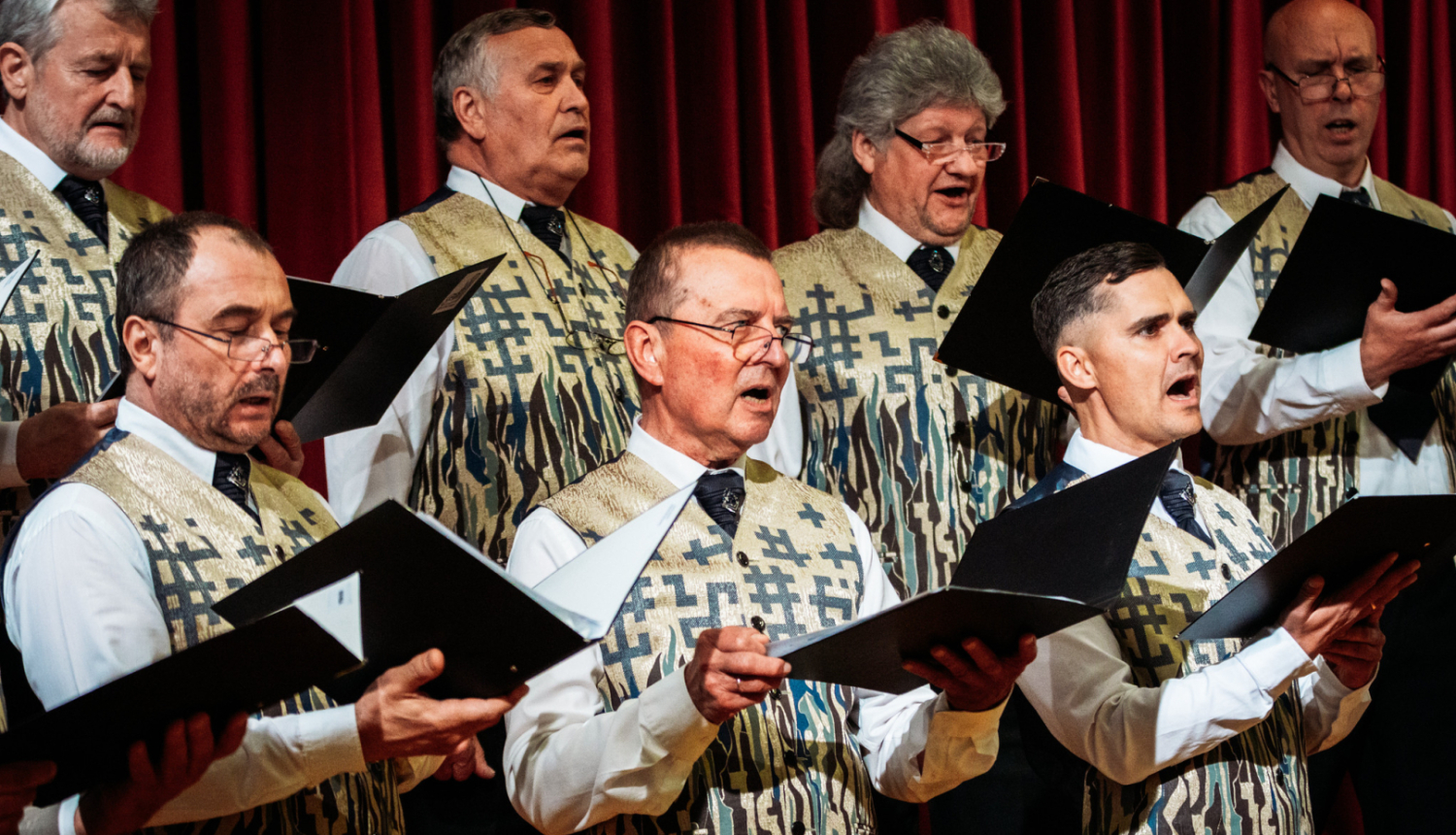 vīrieši tur rokās mapi un dzied