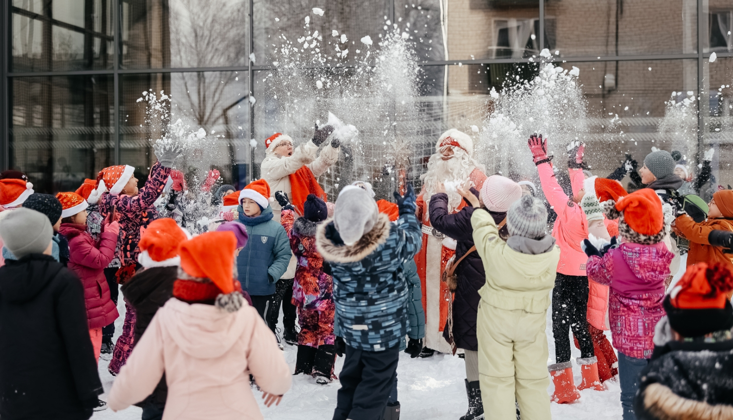 bērni kopā ar Ziemassvētku vecīti met gaisā sniegu