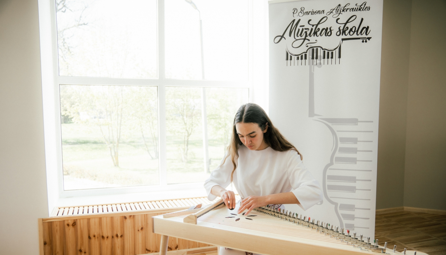 meitene baltā tērpā spēle kokli Aizkraukles mūzikas skolā