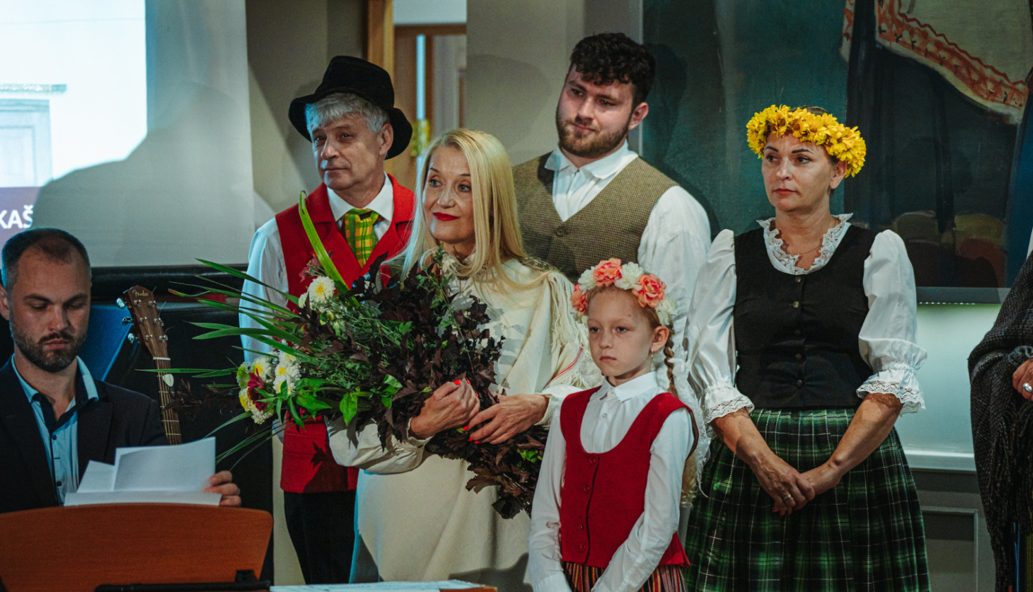 cilvēki stāv pie klavierēm un skatās
